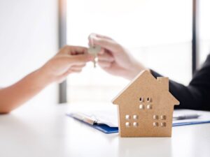 a man and woman sitting at a table with a house model