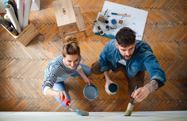 a man and woman painting on a wooden floor