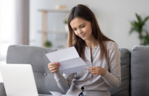 a woman sitting on a couch with a laptop and a piece of paper