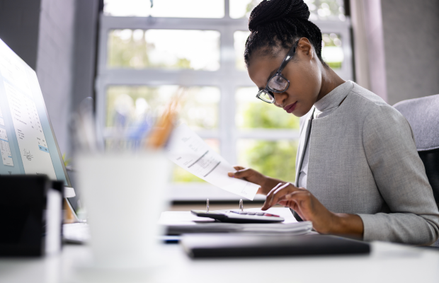 a woman sitting at a desk with a laptop and a cell