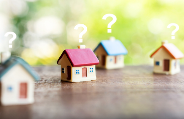 a row of miniature houses with question marks on them