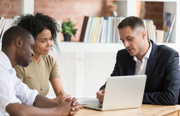 two people sitting at a table looking at a laptop