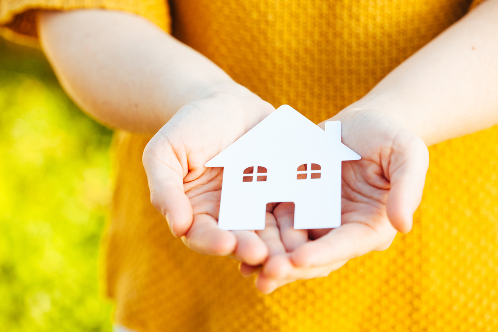 a child holding a paper house in her hands