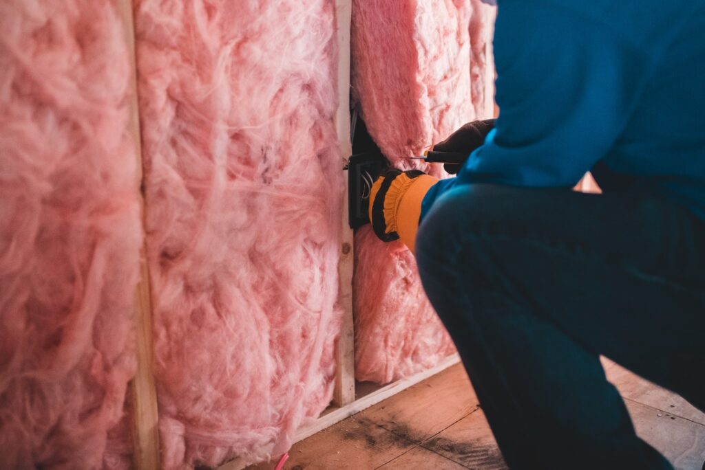 a man in a blue shirt and black pants is working on insulation