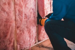 a man in a blue shirt and black pants is working on insulation