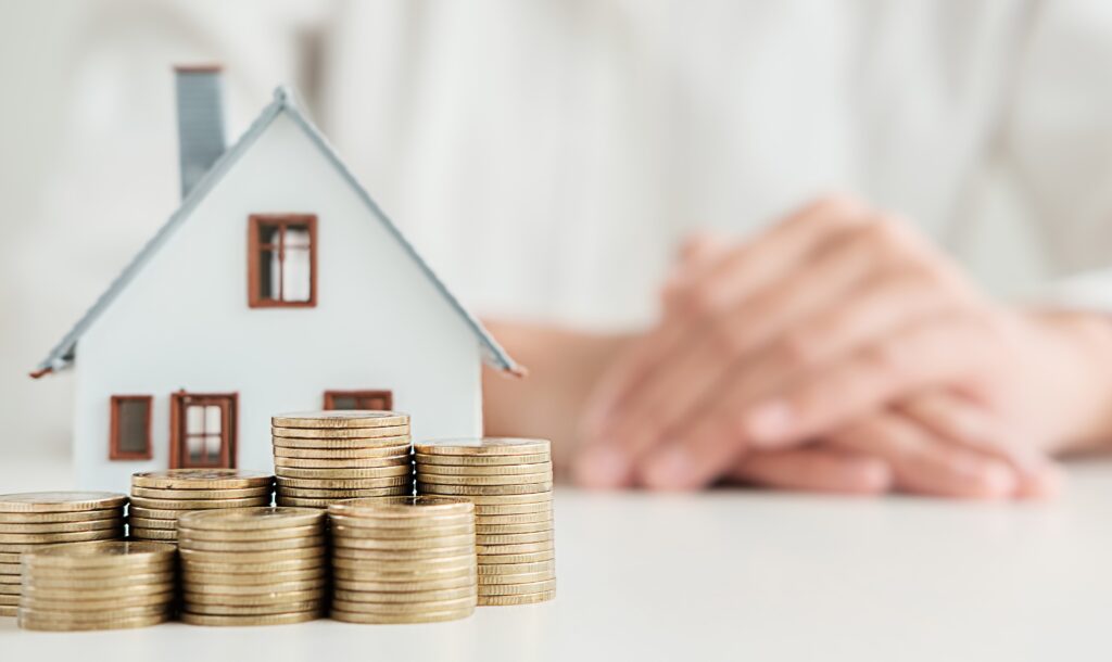 a woman sitting at a table with stacks of coins and a house
