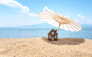 a beach scene with a house and umbrella