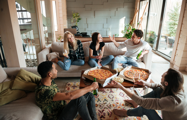 a group of people sitting on a couch eating pizza