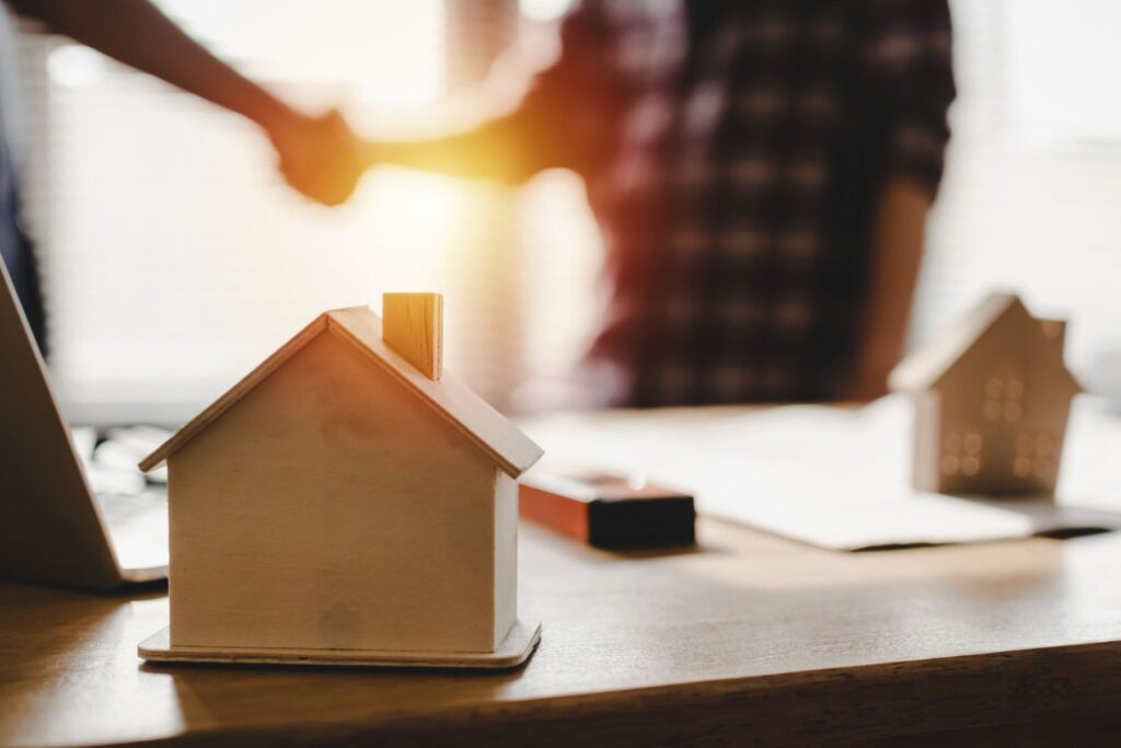 a man and woman shaking hands over a table with miniature houses