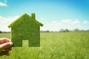 a person holding a green house in their hand