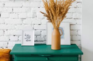 a green dresser with a vase and a plant