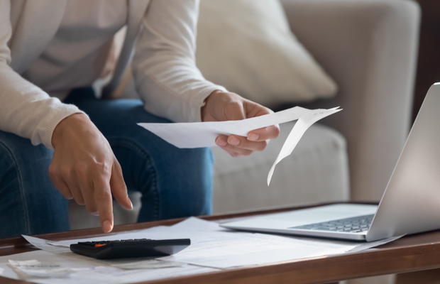 a person sitting on a couch with a laptop and papers