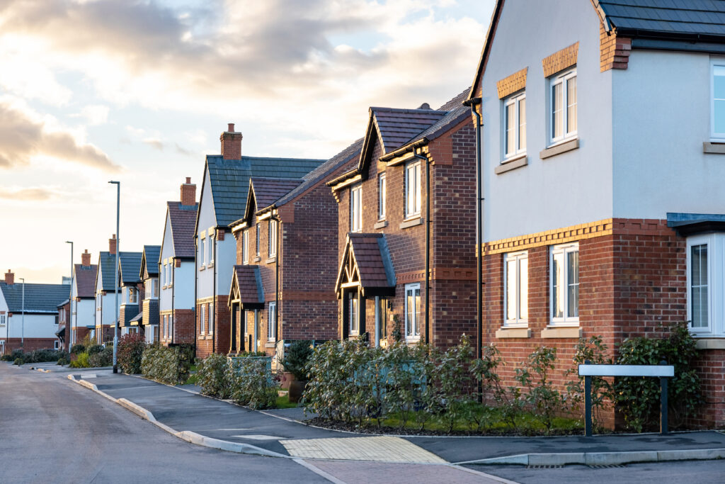 A row of houses illuminated by evening light along a quiet street, creating a serene urban atmosphere.