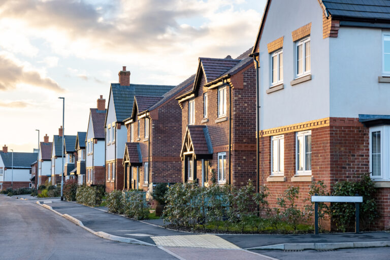 A row of houses illuminated by evening light along a quiet street, creating a serene urban atmosphere.