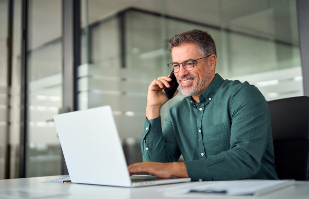 a man sitting at a table with a laptop and a cell