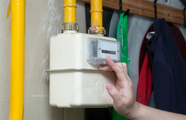 a man in a blue shirt is holding a white water meter