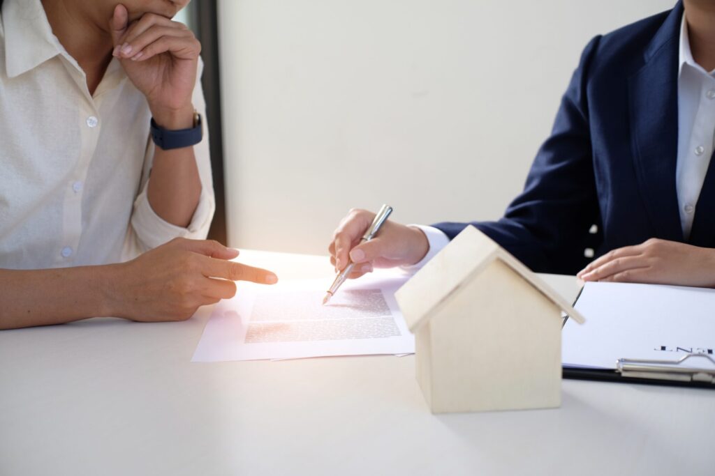 Landlord reviewing an insurance agreement with an advisor, with a model house on the table