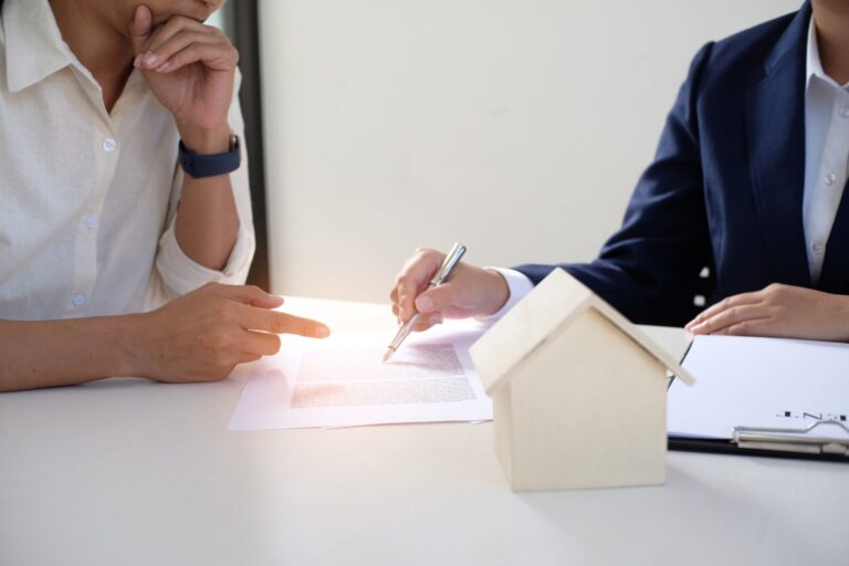 Landlord reviewing an insurance agreement with an advisor, with a model house on the table