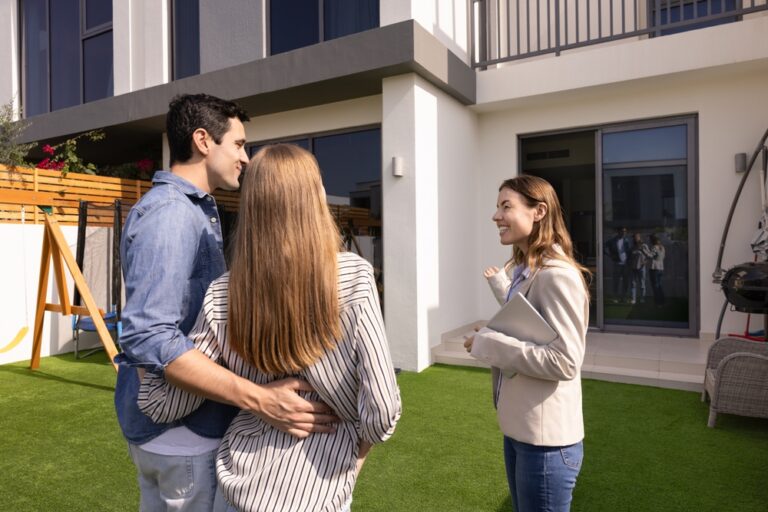 Couple standing together in front of a house.