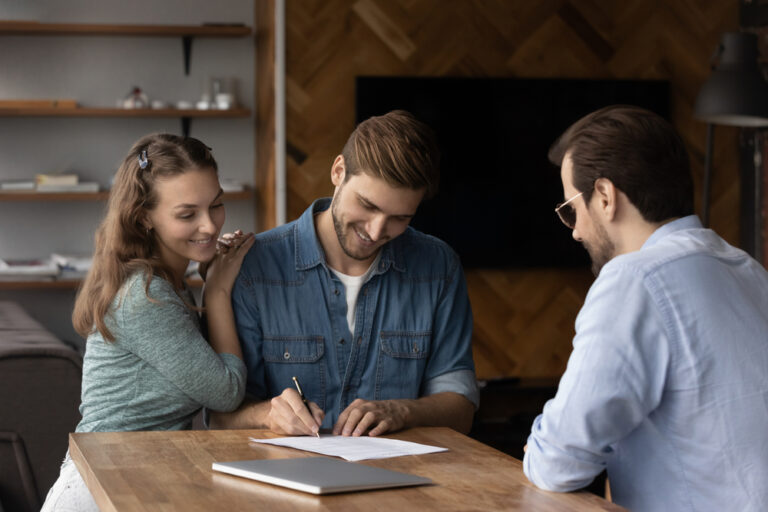 A couple signing a contract with a man and woman present.