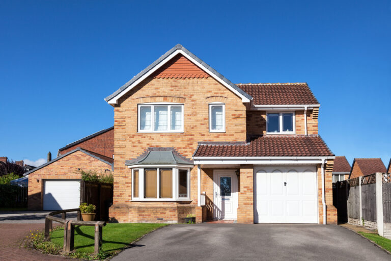 Large brick home with a garage and driveway, featured in a blog post.