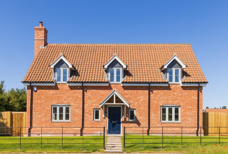 A large, red brick house with a sloped roof and white trim.