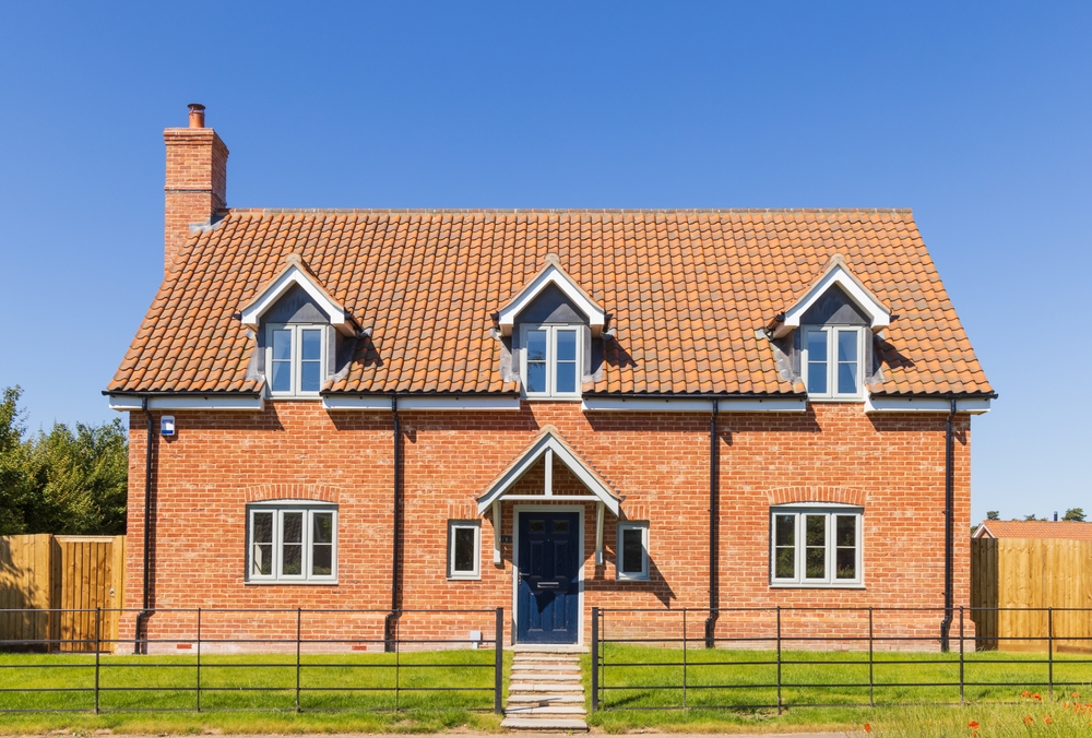 A large, red brick house with a sloped roof and white trim.