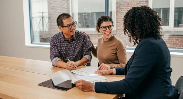 Smiling couple meeting with a letting agent at a desk, reviewing rental property documents