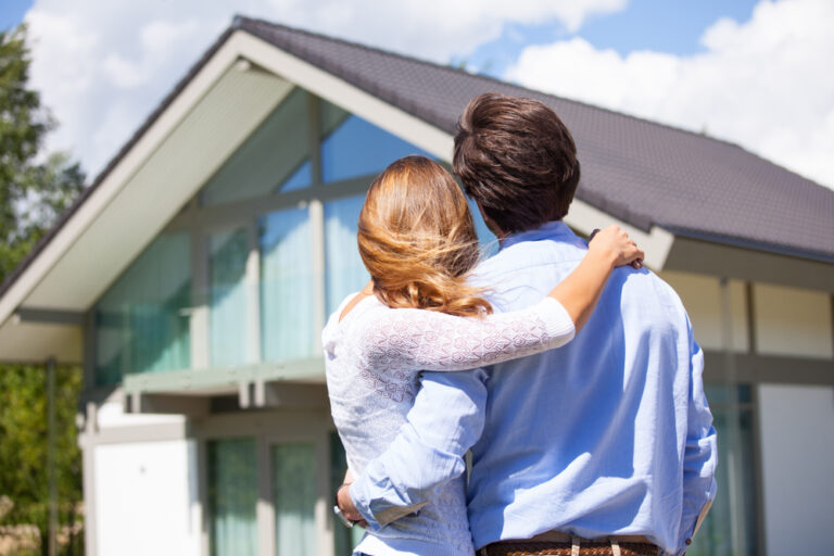 a-man-and-woman-stand-together-in-front-of-a-house