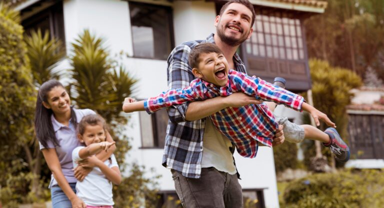 Smiling family playing together in the garden outside their home, reflecting the appeal of Bethnal Green for first-time buyers.