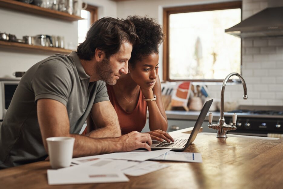 Couple reviewing tenancy paperwork on a laptop in their kitchen, representing landlords preparing for Renters’ Rights Act compliance.