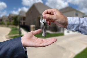 A man hands a key to another person, symbolizing a transfer of responsibility.