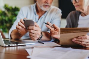 Older couple engaged with a laptop and cellphone, sharing a moment together.