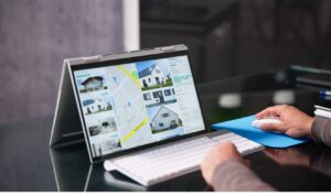 Person browsing houses for sale on a property website using a laptop, with map view and home listings displayed on screen