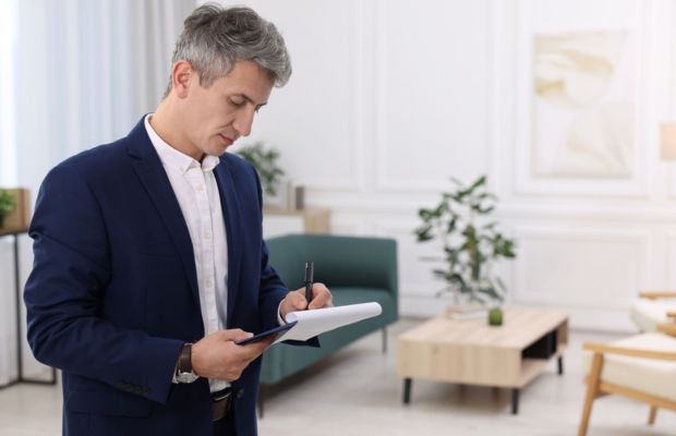 Man in suit writing on a notepad indoors.