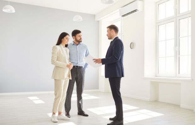 Three people discussing in an empty room.