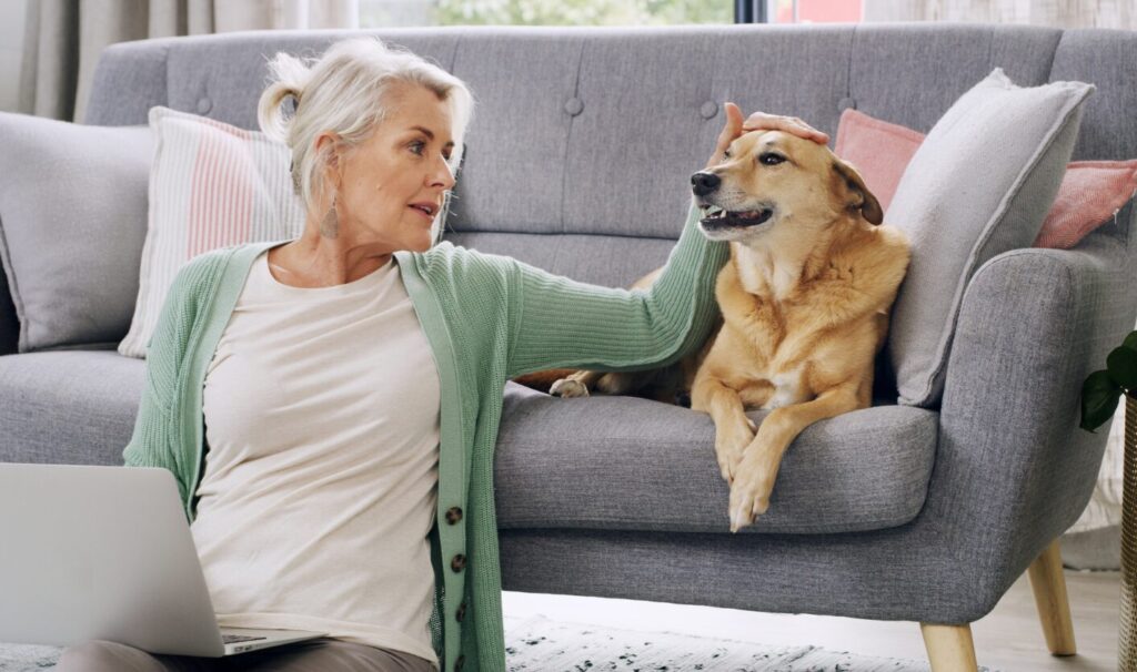 Tenant sitting on the floor beside a sofa stroking her dog in a rental home, reflecting new pet request rules under the Renters’ Rights Act 2025