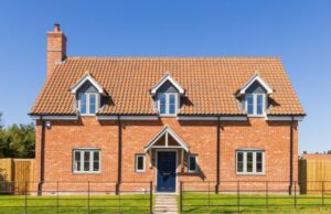 A red brick house surrounded by a fence with a gate in front.