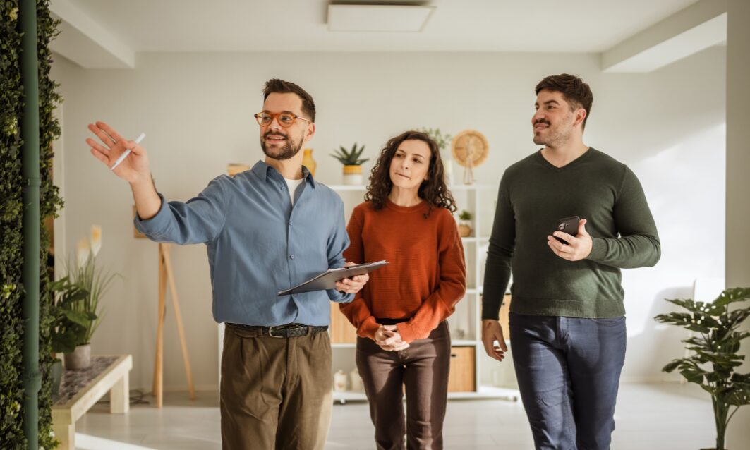 Estate agent showing a couple around a modern home during a property viewing