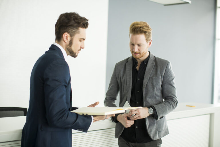 Landlord and tenant discussing paperwork with a letting agent, representing complaint handling and dispute resolution in the UK rental sector