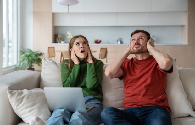 Couples disturbed due to loud noice, sitting on a couch