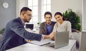 A property agent discussing information on a laptop with a couple, representing professional guidance for Bounds Green landlords staying compliant under the new Property Portal rules.
