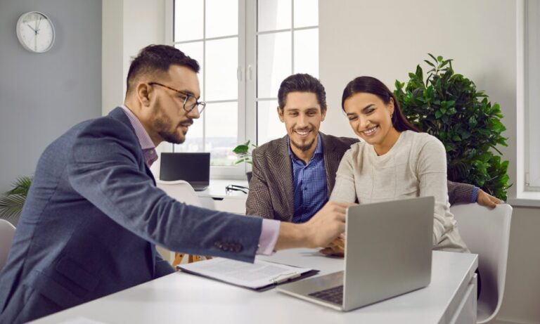 A property agent discussing information on a laptop with a couple, representing professional guidance for Bounds Green landlords staying compliant under the new Property Portal rules.
