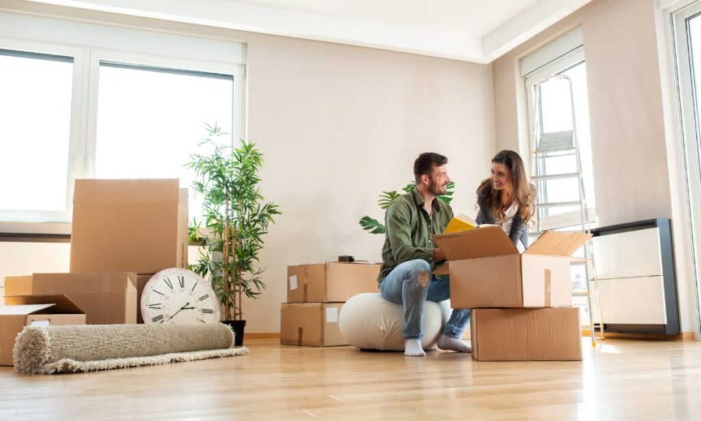 Couple unpacking boxes in a bright home, representing Golders Green buyers planning stamp duty and moving costs in London.