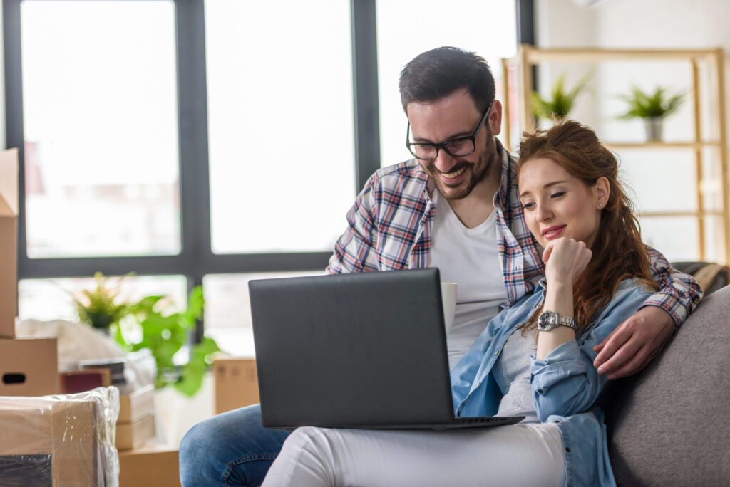 Couple using a laptop in their new home, representing buyers comparing new-build and period properties in Tonbridge.