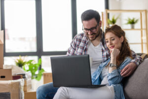 Couple using a laptop in their new home, representing buyers comparing new-build and period properties in Tonbridge.