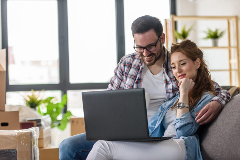 Couple using a laptop in their new home, representing buyers comparing new-build and period properties in Tonbridge.