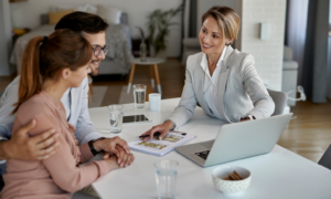 Homeowners meeting with an estate agent to discuss selling their property and review property details.
