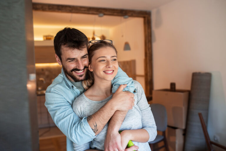 Young couple standing together in a bright, modern home filled with natural daylight.