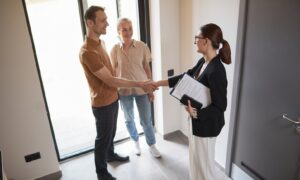 Estate agent greeting a couple inside a bright modern home